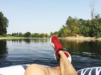 Low section of man in lake against clear sky