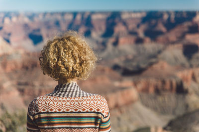 Rear view of woman with curly hair against landscape at grand canyon national park