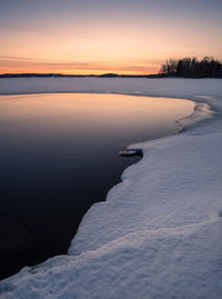 Scenic view of frozen lake against sky during sunset