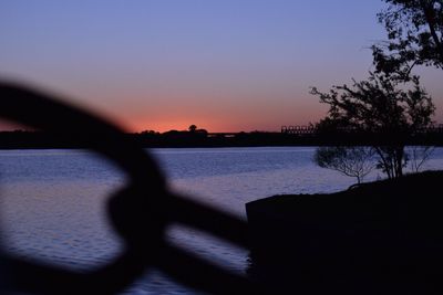 Close-up of silhouette tree by lake against sky