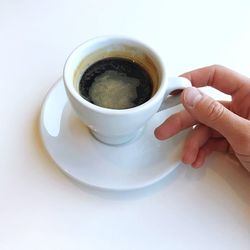 Cropped image of person holding coffee cup on table