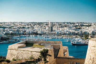 Aerial view of buildings in city against clear blue sky