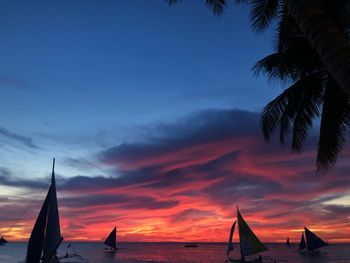 Silhouette sailboat on beach against sky during sunset