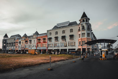 Road by buildings in town against sky