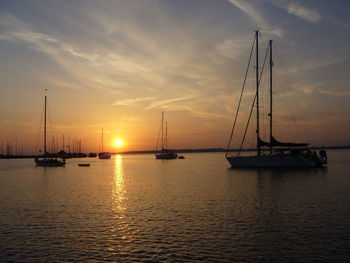 Sailboats sailing on sea against sky during sunset