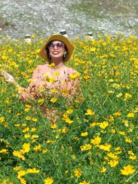 Portrait of smiling young woman with yellow flowers in field
