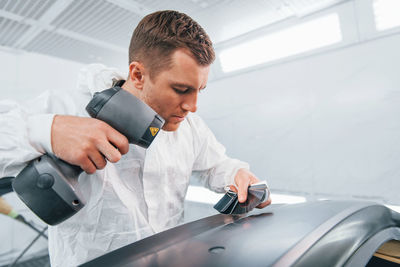 Painting the car. man in uniform is working in the auto service.