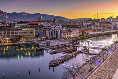 Bridge over river in city against sky during sunset