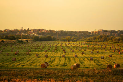 Hay bales on field against sky during sunset