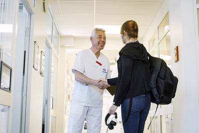 Male doctor shaking hands with female patient on routine check up in medical clinic