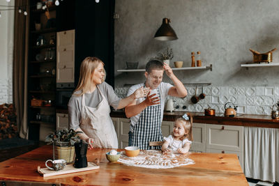 Funny happy dad and daughter baby cook together fool around and play with flour in  kitchen at home