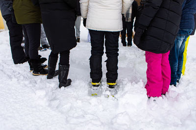 Low section of women standing on snow covered people