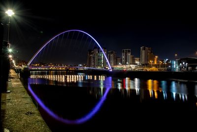 Illuminated bridge over river at night