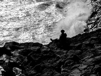 Man sitting on rock by sea