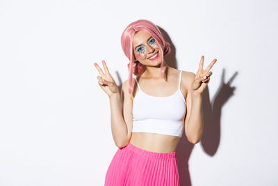 Portrait of young woman standing against white background