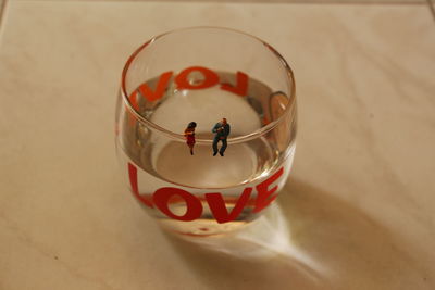 High angle view of figurines on drinking glass over table