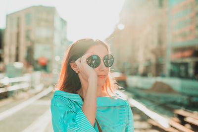 Young woman in sunglasses standing at city