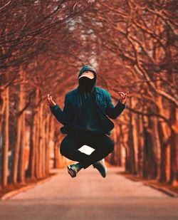 Full length of man jumping against trees