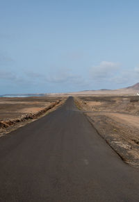 Road amidst desert land against sky