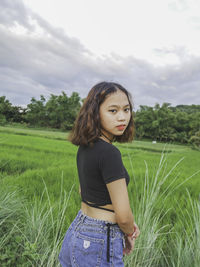 Happy woman standing on land against sky