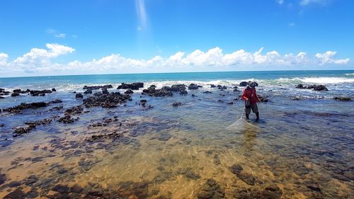 Rear view of man on beach against sky