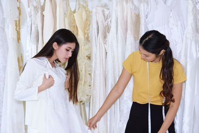 Bride with owner choosing wedding dress at bridal shop