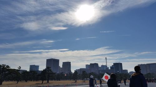 People in park by buildings in city against sky