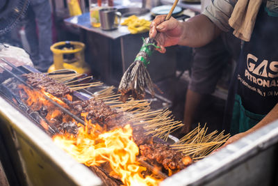 Midsection of man preparing food on barbecue grill