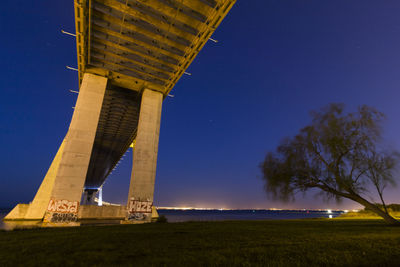 Low angle view of bridge over river at night