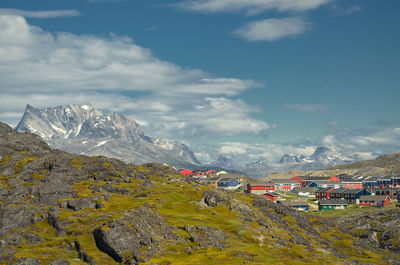 Scenic view of houses by mountains against sky