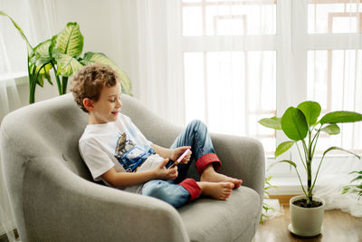Boy using smart phone sitting on couch