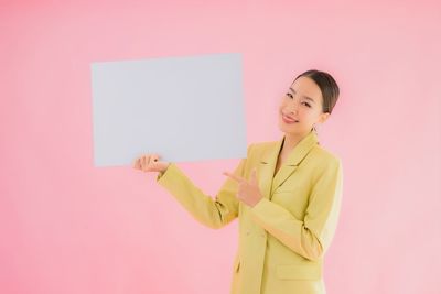 Portrait of a smiling young woman against pink background