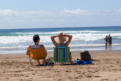 Rear view of people sitting on beach