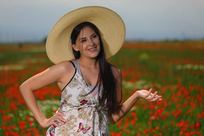 Portrait of smiling young woman wearing hat standing on field