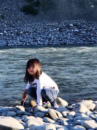 Girl sitting on rock by sea