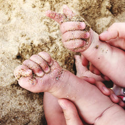 Cropped hands of woman and baby at beach