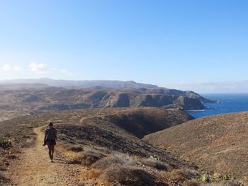 Woman hiking on mountain at santa catalina island against blue sky