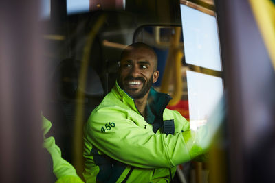 Smiling male paramedic looking away while driving ambulance in parking lot