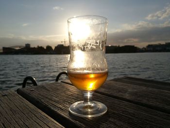 Close-up of beer glass on table against sky during sunset