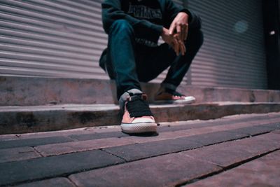 Low section of man sitting on footpath