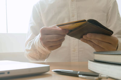 Midsection of man reading book on table