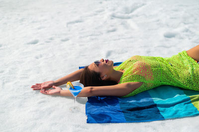 Rear view of woman sitting on sand at beach