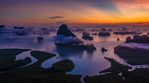 Rocks in sea against sky during sunset