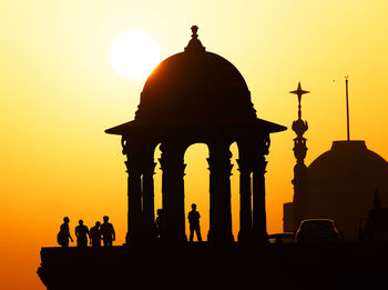 Silhouette of people at gazebo against sky during sunset