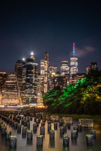 Illuminated modern buildings in city against sky at night