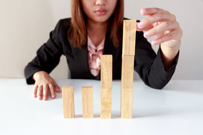 Midsection of businesswoman stacking wooden toy blocks