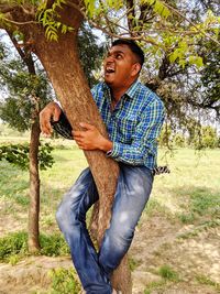 Full length of young man on tree trunk in field