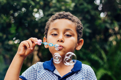 Boy blowing bubbles in park