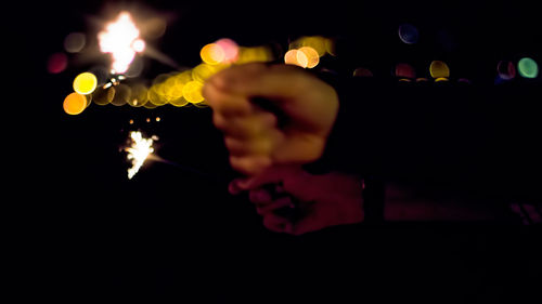 Close-up of hand holding illuminated lights at night