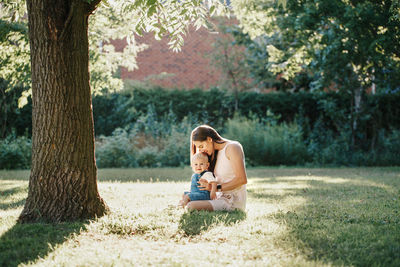 Mother and son sitting by tree at park